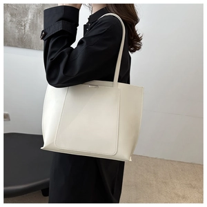 Detail of cream white tote bag with silver buckle and fine stitching on a black outfit