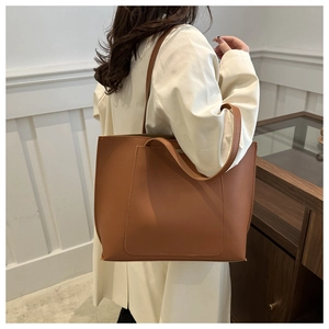 Detailed side view of a large brown leather tote bag worn as a shoulder bag