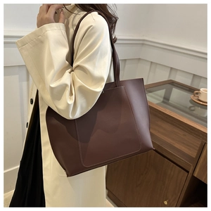 Detail of deep brown tote bag showing smooth synthetic leather and rectangular patch