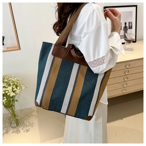 Detail view of the striped tote bag with leather corners in a warm home setting