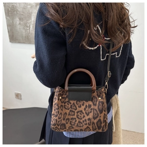 Vista posteriore di una borsa leopardata con manico marrone e tracolla nera su maglione