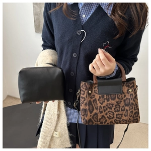Detail of leopard print tote with wooden handles and matching black cosmetic pouch