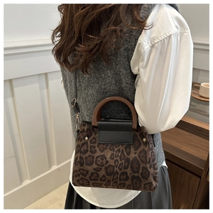 Dettaglio borsa leopardata con manico rotondo in legno e chiusura in metallo