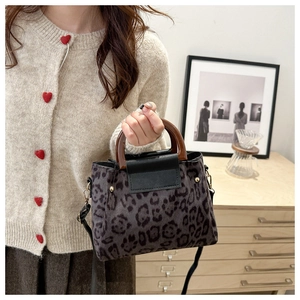Dettagli di una borsa leopardata con manici in legno e texture scamosciata marrone