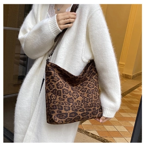 Side view of large leopard print tote bag with brown shoulder strap on white cardigan