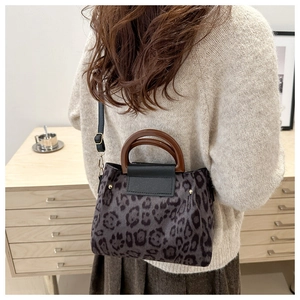 Dettaglio della borsa leopardata con manico rotondo in legno e decorazione con rivetti