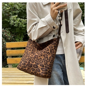Close-up of leopard print tote bag with adjustable brown strap shown in outdoor setting