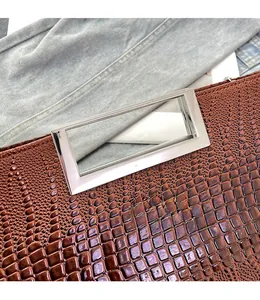 Close-up of brown crocodile pattern embossed leather handbag with silver rectangular handle