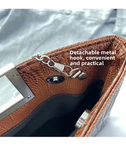 Detail of brown crocodile pattern handbag with detachable silver metal hook and magnetic snap