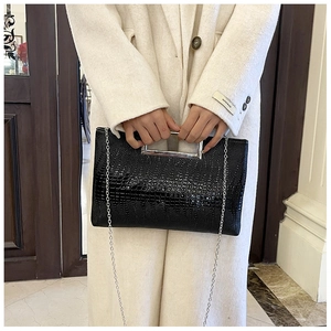 Detail of black crocodile texture handbag with silver metal handle and chain strap