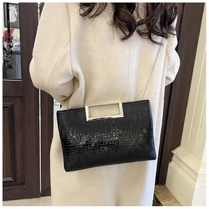 Detail of black crocodile texture leather bag with elegant metallic handle on white coat