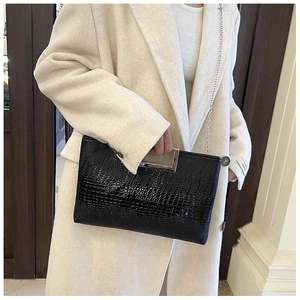 Detail of crocodile pattern evening bag with silver handle held by a model in a beige coat