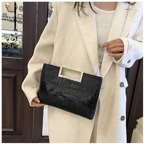 Detail of crocodile-patterned handbag with silver rectangular handle and chain strap
