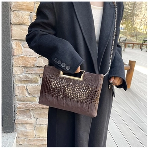 Detailed texture of dark brown crocodile pattern handbag with gold metal handle
