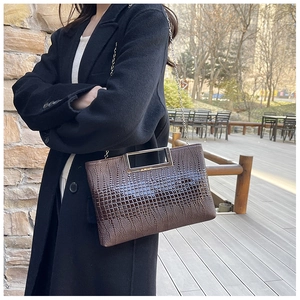 Detail of dark brown croc-embossed bag with gold rectangular handle and chain strap