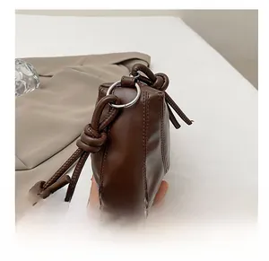 Détail de l'anneau métallique argenté et de la sangle nouée du sac en cuir marron