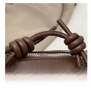 Détail du nœud de la bandoulière en cuir et de la fermeture éclair argentée du sac brun