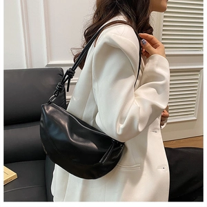 Gros plan sur un sac selle noir en cuir avec nœud décoratif sur une bandoulière