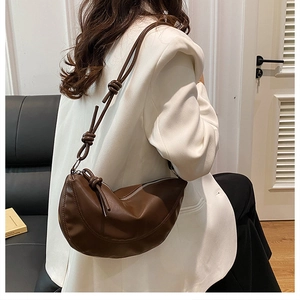 Détail du sac demi-lune marron avec bandoulière nouée et boucles argentées sur modèle