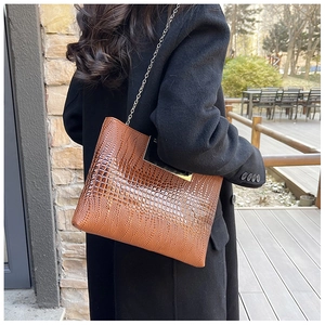 Close-up of a brown crocodile pattern crossbody bag with a gold chain and metal frame clasp