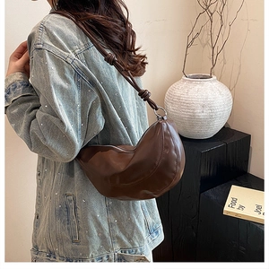 Détail du sac demi-lune marron foncé avec bandoulière à nœud et boucles argentées