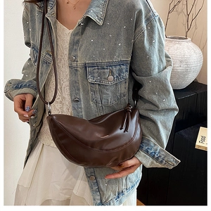 Détail du sac selle demi-lune marron foncé avec bandoulière nouée porté par le mannequin