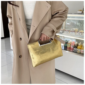 Detail of gold crocodile embossed leather handbag with metallic top handle and chain strap