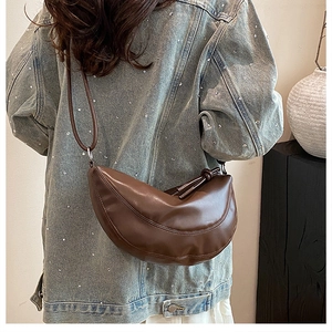 Détail du sac demi-lune en cuir PU marron avec nœud latéral et surpiqûres incurvées