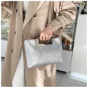 Detail of silver crocodile-textured handbag with metallic handle and chain shoulder strap
