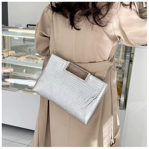 Detail of silver crocodile pattern handbag with metallic handle and chain shoulder strap