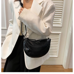 Sac bandoulière demi-lune noir minimaliste assorti à un blazer blanc pour femme