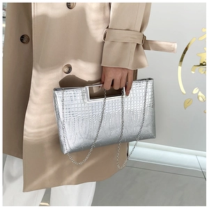 Detail of silver crocodile-patterned evening bag with metallic finish and metal handle