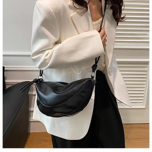 Détail du sac bandoulière croissant noir avec nœud stylé et texture en cuir synthétique
