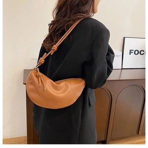 Détail du sac demi-lune en cuir marron avec bandoulière à nœud décoratif sur mannequin