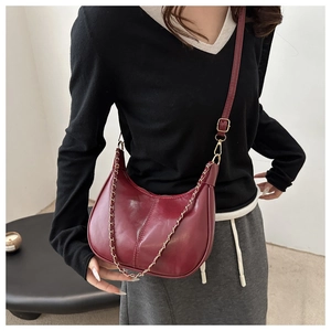 Détail du sac bandoulière bordeaux en forme de croissant avec chaîne dorée
