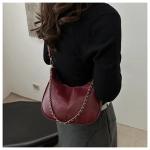 Détail macro du sac sous le bras en cuir rouge foncé avec chaîne dorée et fermeture éclair