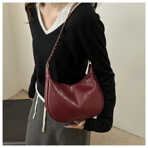 Détail d'un sac hobo bordeaux avec bandoulière chaîne dorée et coutures élégantes