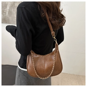 Détail du sac hobo croissant marron vintage avec chaîne dorée et bandoulière en cuir