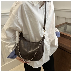 Détail d'un sac demi-lune marron avec coutures verticales et chaîne dorée élégante