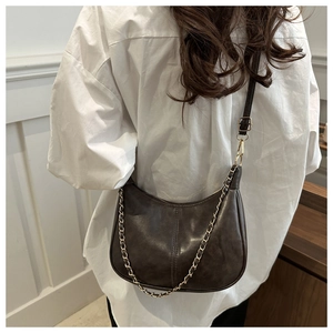 Détail d'un sac demi-lune marron foncé avec chaîne dorée et bandoulière réglable