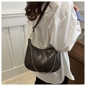 Détail du sac rétro marron foncé montrant la forme demi-lune et la chaîne dorée