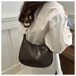 Détail d'un sac demi-lune marron foncé rétro avec simili cuir antique et chaîne