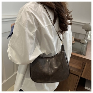 Détail du sac demi-lune marron vintage avec bandoulière chaîne porté par un mannequin