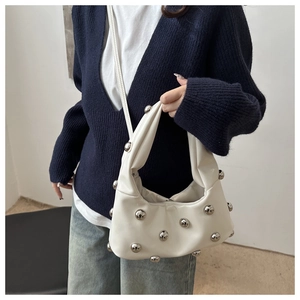 Detail of white faux leather shoulder bag featuring stylish silver bead embellishments