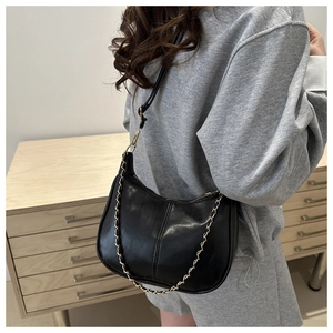 Détail du sac sous le bras noir en demi-lune avec simili cuir brillant et chaîne en métal