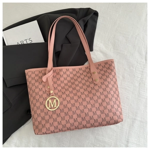 Detail of pink tote bag with M letter prints and gold logo charm on white fabric
