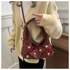 Detail of dark red Hobo bag featuring large silver studs and smooth glossy leather finish