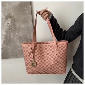 Macro detail of pink leather tote bag featuring repeating M logo print and gold charm