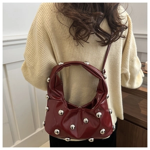 Close-up of crescent moon shoulder bag in burgundy patent leather with silver studs