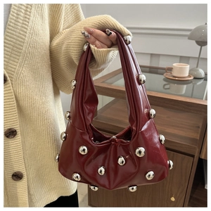 Detail of burgundy glossy leather underarm bag with silver metallic sphere embellishments